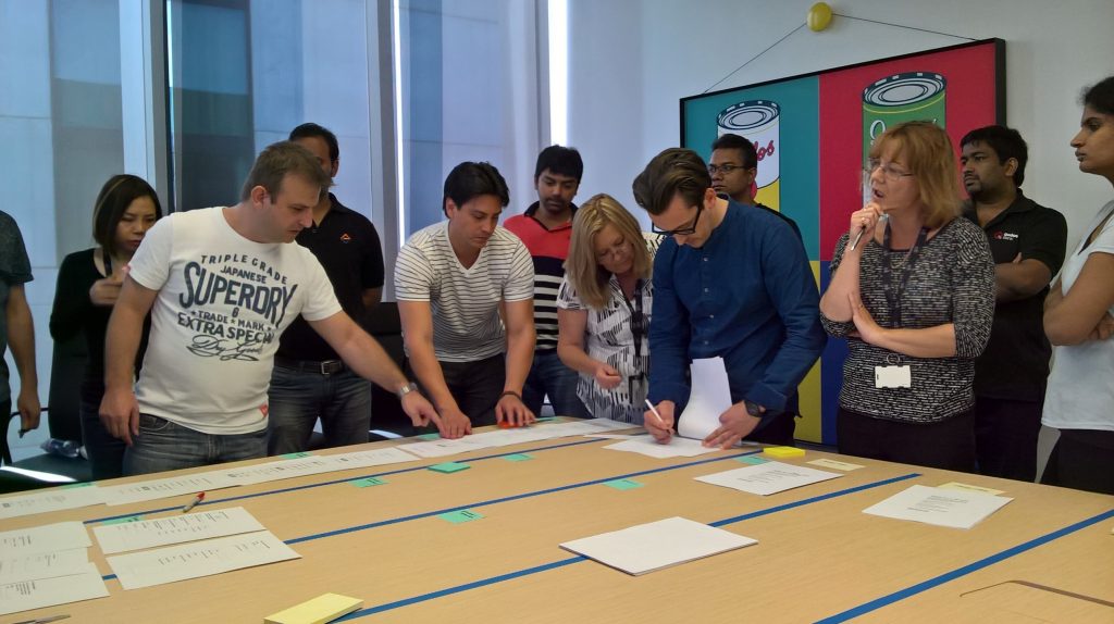 Numerous business stakeholders and designers collaborating together in an effort to resolve an issue during a design workshop